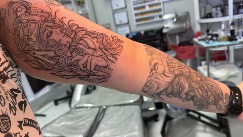 Tattoo artist working on a detailed arm tattoo during a session