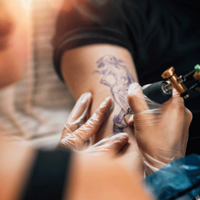 Tattoo artist creating a custom tattoo design using professional equipment in a clean studio environment