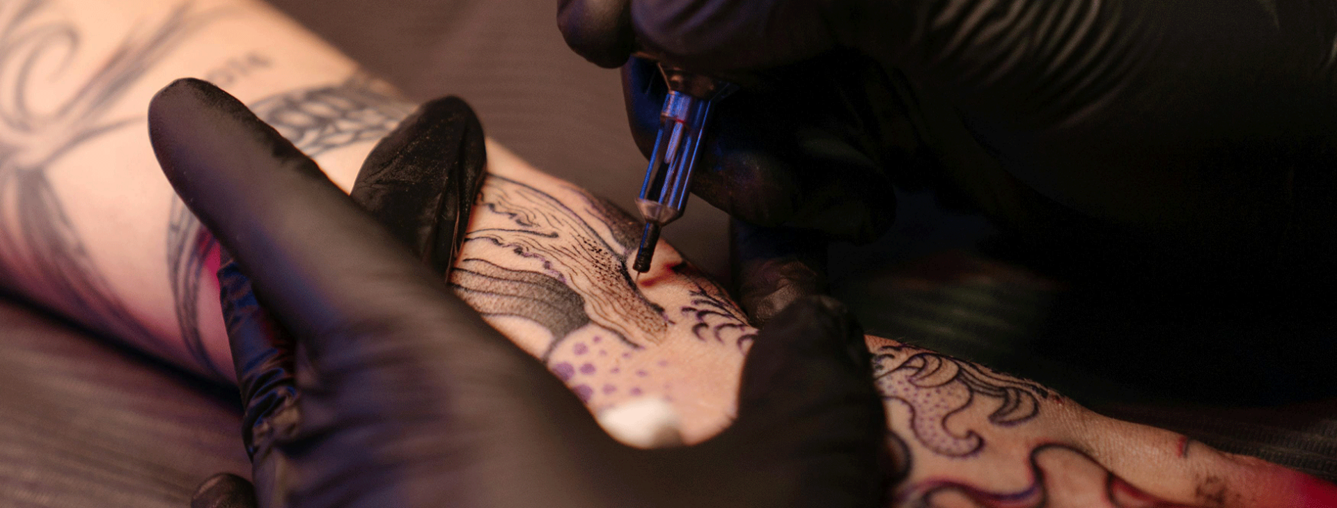Tattoo artist applying detailed linework and shading during a custom tattoo session