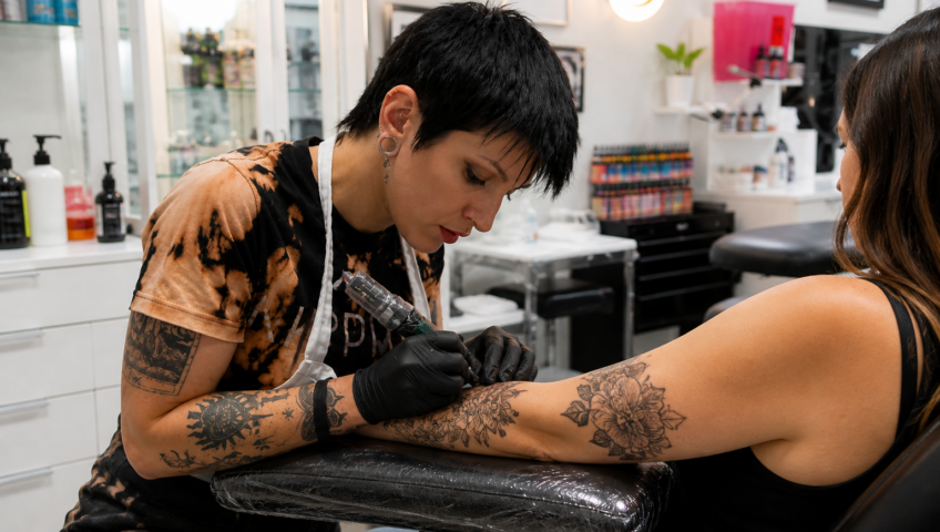 Female tattoo artist creating a custom tattoo in a clean professional studio in Lafayette LA